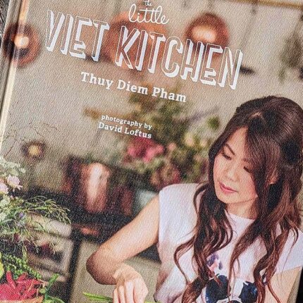Author Thuy Pham smiling warmly while showcasing her beautiful new cookbook during a literary dining event in Essex.