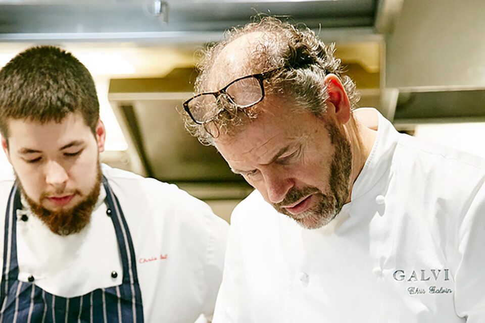 Professional chefs meticulously plating a sophisticated dish in a bustling fine dining kitchen