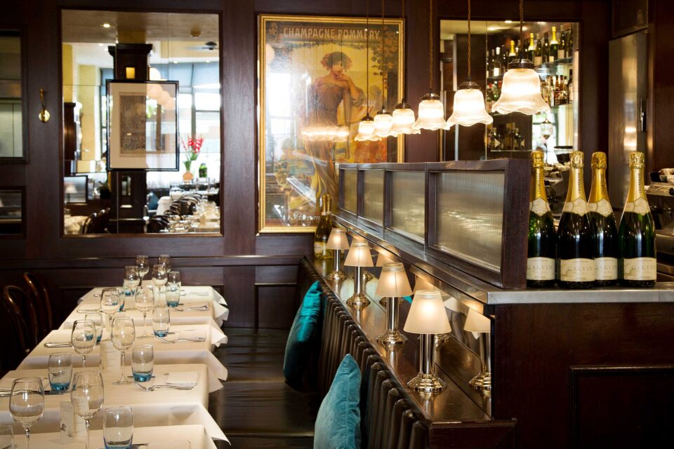 The elegant, warmly lit exterior facade of a classic French-inspired dining establishment