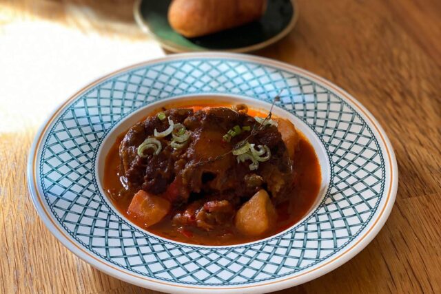 Rich, slow-cooked spicy oxtail stew garnished with fresh herbs by Galvin Restaurants.