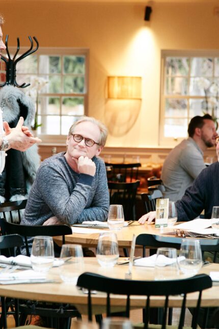 A Galvin La Chapelle chef warmly interacting with guests in the elegant dining room, reflecting our commitment to hospitality and community support.