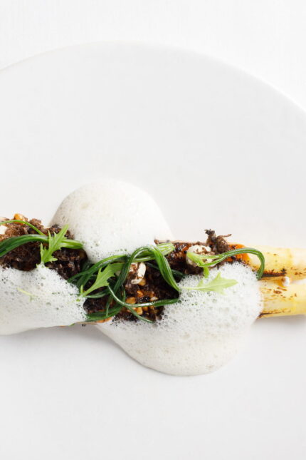 A delicate dish of roasted white asparagus topped with a savoury crumble and a light culinary foam.