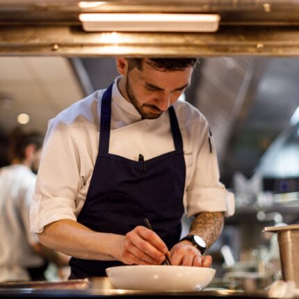 A masterful chef delicately plating an exquisite fine dining course with absolute precision.
