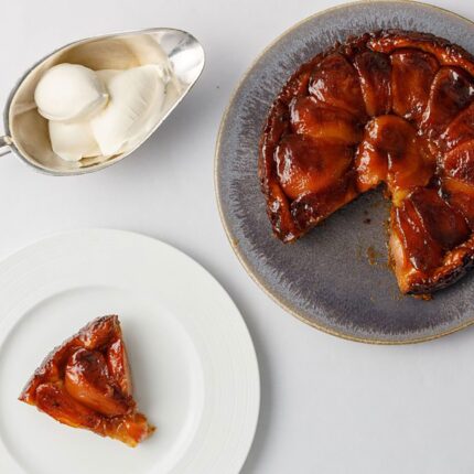 A beautifully caramelised apple tarte tatin served gracefully alongside a delicate quenelle of fresh cream.