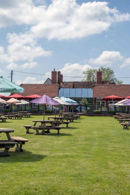 Guests enjoying the outdoor beer garden and parasols at our countryside dining venue.