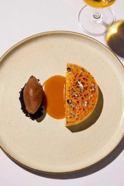 Decadent creme brulee tart served with a chocolate quenelle and caramel drizzle as part of The Autumn Table four-course menu in London.