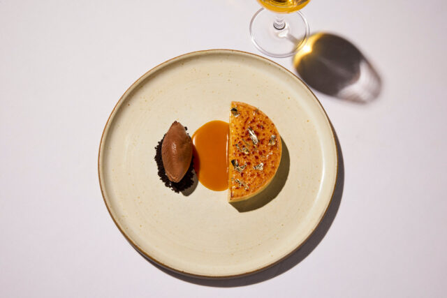 Decadent creme brulee tart served with a chocolate quenelle and caramel drizzle as part of The Autumn Table four-course menu in London.