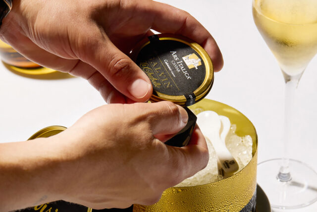 Small tin of caviar served on ice, accompanied by blinis, chopped chives, and a glass of champagne at Galvin La Chapelle.