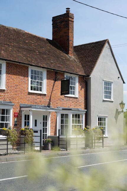 Exterior view of the traditional brick Galvin Green Man pub with white-framed windows and hanging flower baskets.