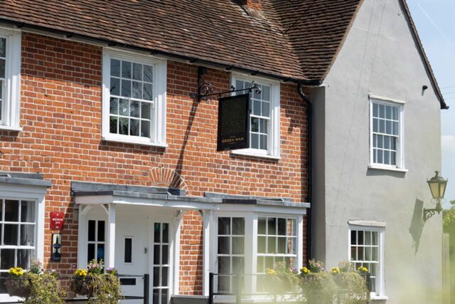 Exterior view of the traditional brick Galvin Green Man pub with white-framed windows and hanging flower baskets.